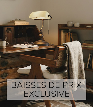Un espace de travail vintage élégant avec un bureau en bois massif, une lampe de table raffinée, des livres et une chaise confortable baignée d'une lumière chaleureuse.