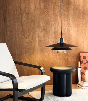 Suspension Dyberg Larsen au-dessus d’une table d’appoint et d’un fauteuil dans une ambiance chaleureuse.