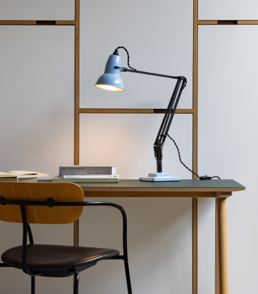 Lampe de bureau Anglepoise bleu clair sur une table en bois avec une chaise