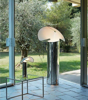 Deux lampadaires brillants avec abat-jour incurvés en forme de feuille devant une fenêtre avec vue sur le jardin.